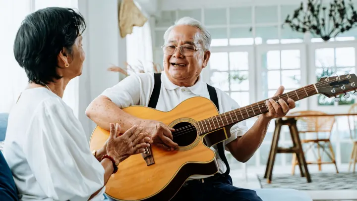 Senior man playing guitar for wife